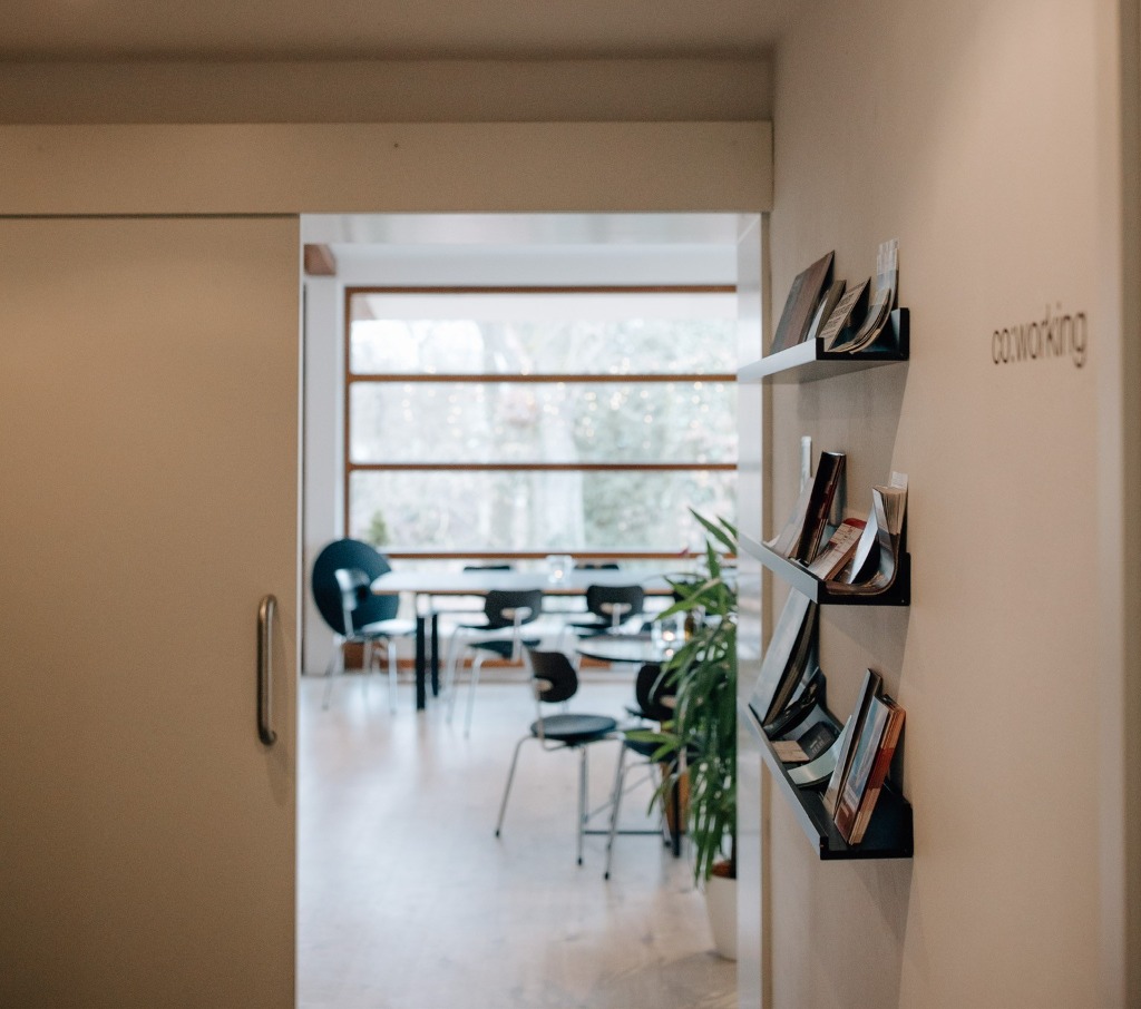 Einladender Flur der co:Lab Villa mit co:working Schriftzug an der Wand und Blick in den hellen, modernen Besprechungs- und Workshopraum